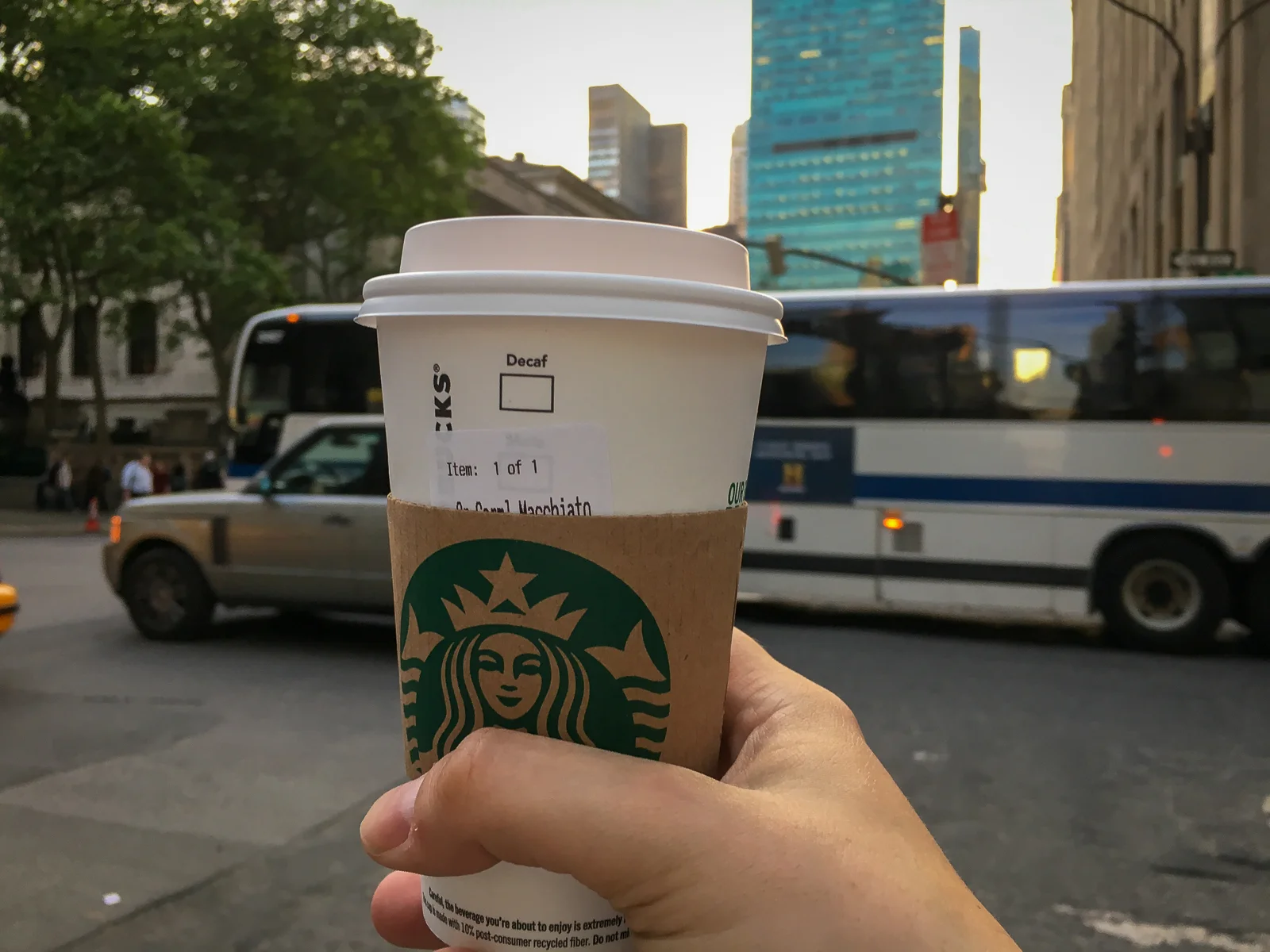Starbucks Kaffee Becher in der Hand vor Hochhäusern in Midtown Manhattan New York City